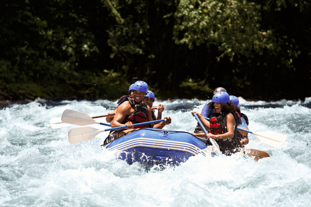 Group of adventurers white-water rafting in Costa Rica, wearing helmets and life jackets, navigating turbulent waters amidst lush greenery.