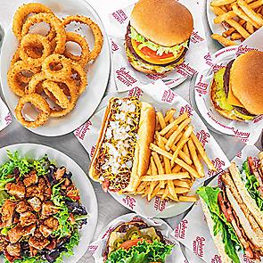 Variety of Johnny Rockets menu items including burgers, onion rings, fries, salad, and shakes, showcasing onboard dining options for Royal Caribbean cruises.